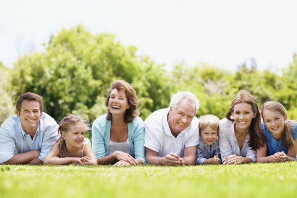 Smiling and happy family lying together on the grass outdoors