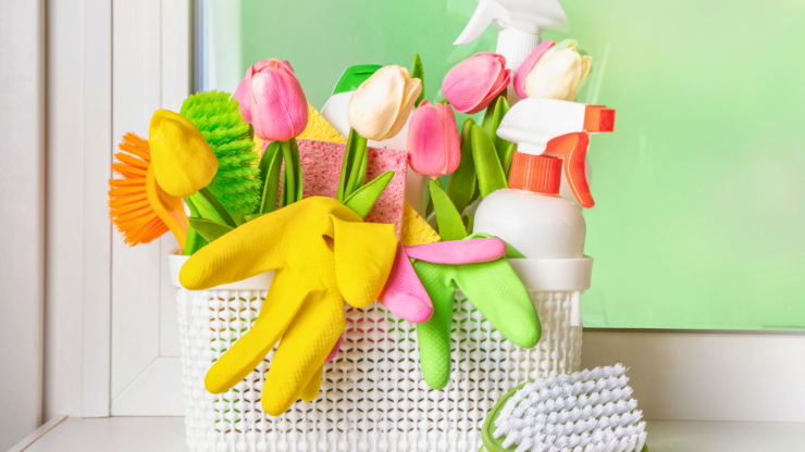 Cleaning supplies in a basket with colorful flowers for a spring cleaning article.