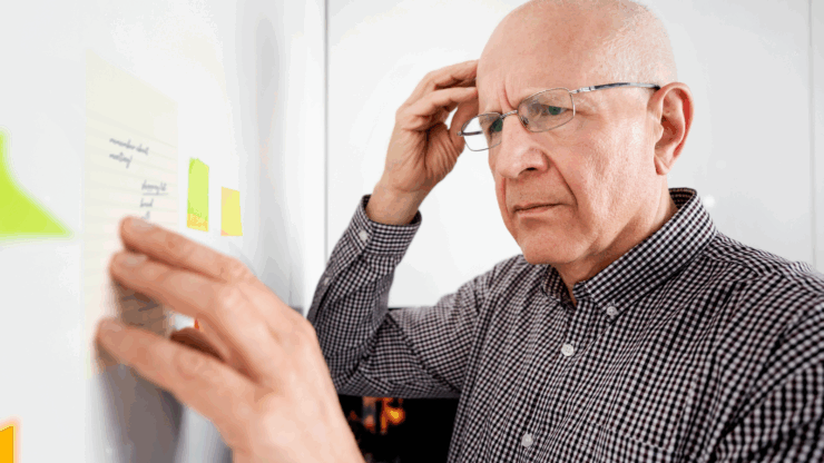 Man touching his head with a confused look while reading notes.